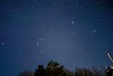 冬の夜空。中央左にオリオン座、右上にプレアデス星団とひときわ明るい星