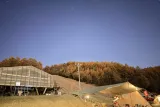 星と自然のフェスタ 2025 の会場。落葉松の林の上に星空、手前に観測テントと望遠鏡（小海）